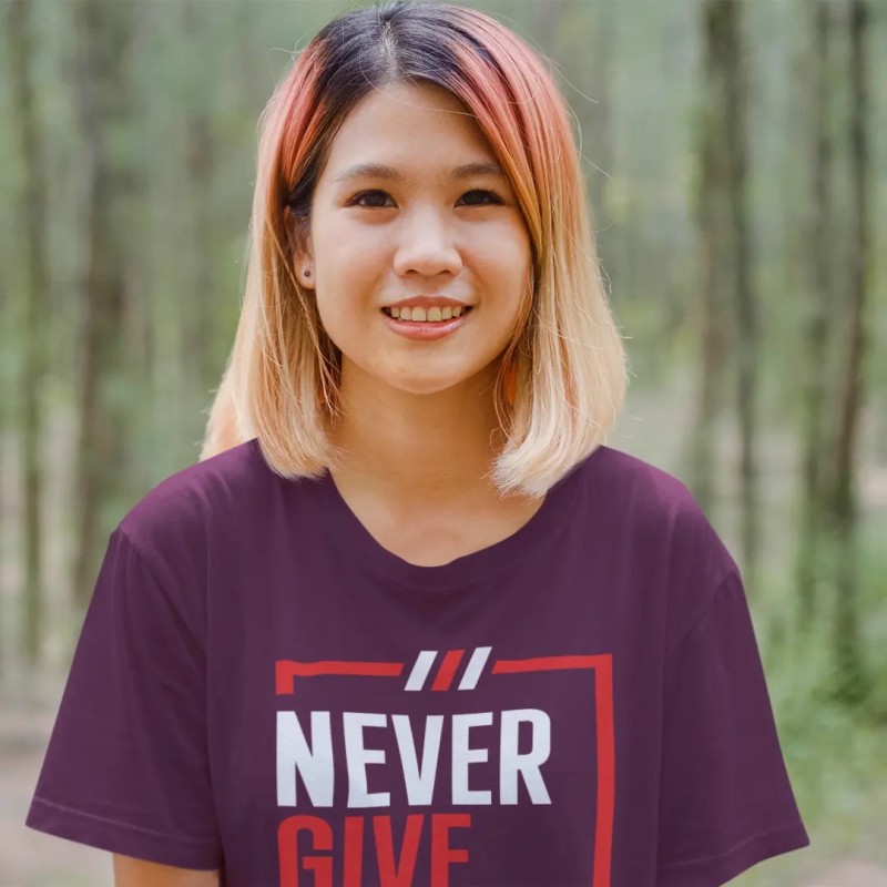 ragazza con lineamenti asiatici che veste la tshirt di ispirazione massima "never give up just keep going" in viola